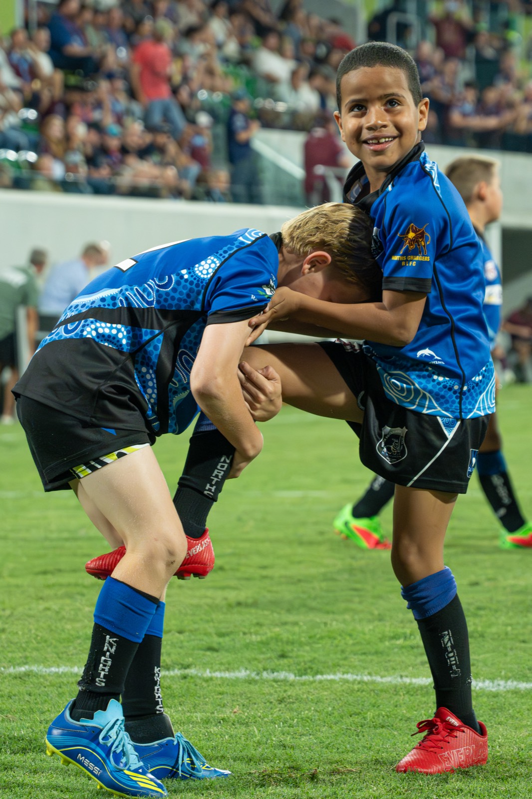 Two junior rugby league players sharing a hug on the field after a match