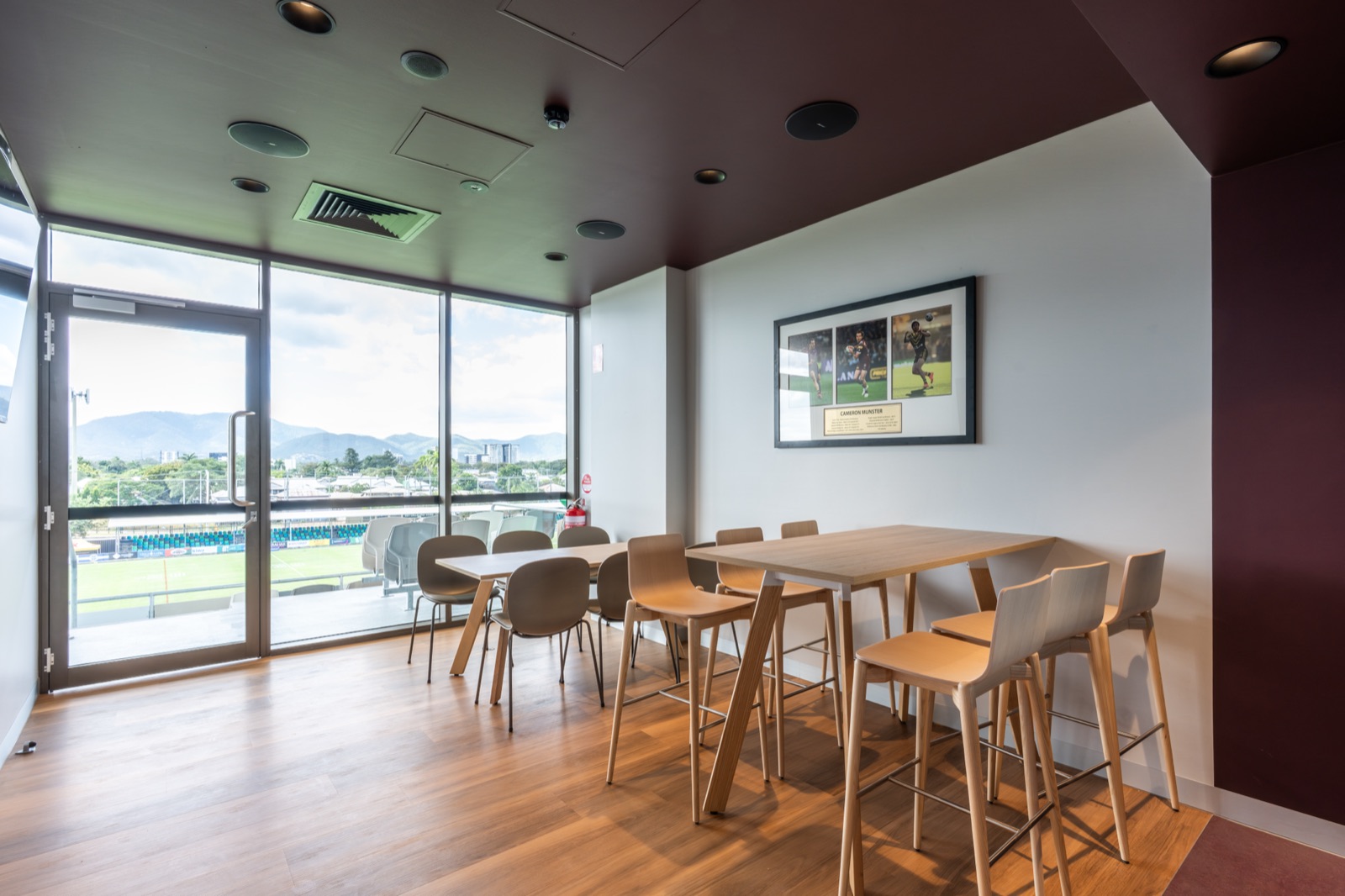 Corporate box hospitality room with dining and high bar tables overlooking Aurizon Stadium